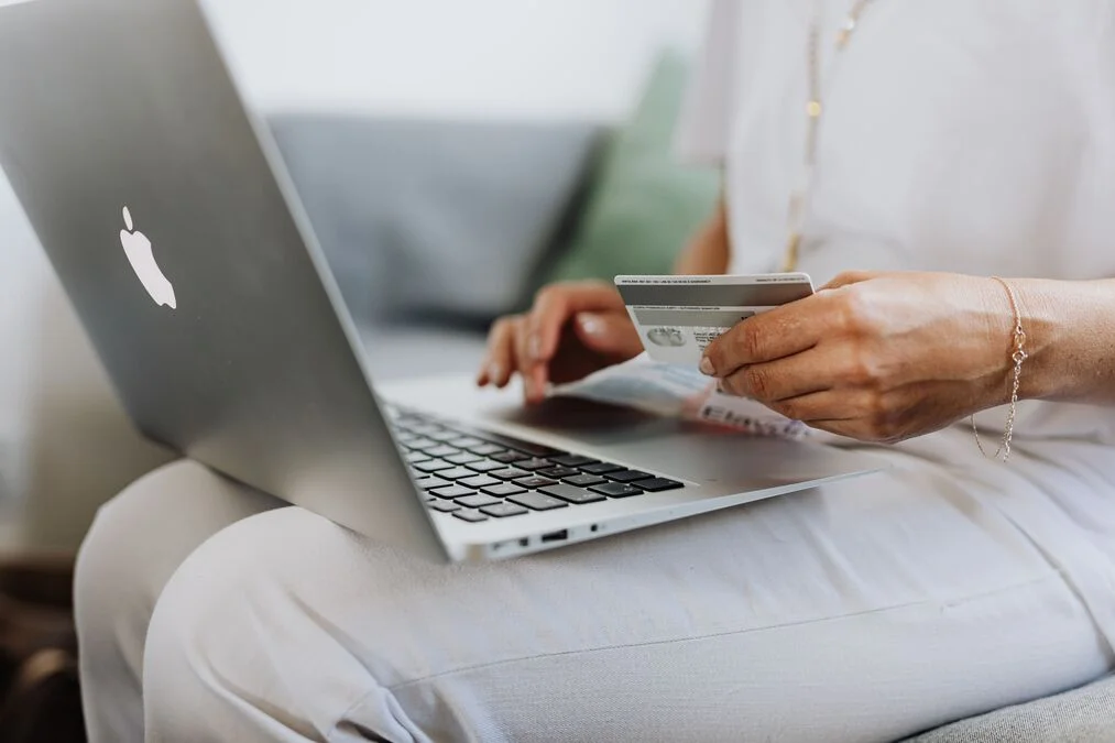 How to apply for a credit card – person holding a credit card while using a laptop online